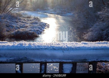 Restes de neige sur le garde-corps d'un pont au-dessus d'un ruisseau gelé en hiver Banque D'Images