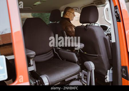 Fauteuil roulant motorisé contre un homme handicapé assis dans une camionnette Banque D'Images