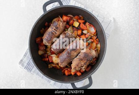 Roulés de bœuf frits avec mirepoix rôti ou légumes-racines dans une rôtissoire prête à cuire ou à braiser. Cuisson, préparation, préparation. Fait partie d'une série Banque D'Images