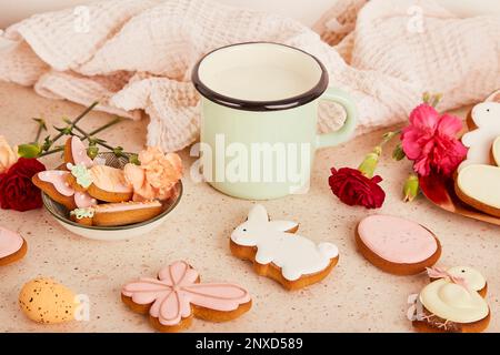 Table de Pâques confortable et esthétique avec une tasse de lait parmi les biscuits et les fleurs. Printemps vacances fond floral Banque D'Images