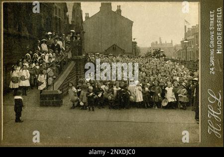La photo ultime de l'école : des centaines d'enfants victoriens ou édouardiens de la fin et leurs enseignants emballent le parvis d'une école à Huddersfield, West Yorkshire, Angleterre, Royaume-Uni. Détail sépia de la carte de cabinet publiée par « H H l », 24 Spring Grove Street, Springwood, Huddersfield. L'emplacement peut être Spring Grove School, fondée en 1879 et toujours en 2024, opérant dans la rue Water comme une école junior, infantile et maternelle. Photographie vintage d'une collection privée. Banque D'Images