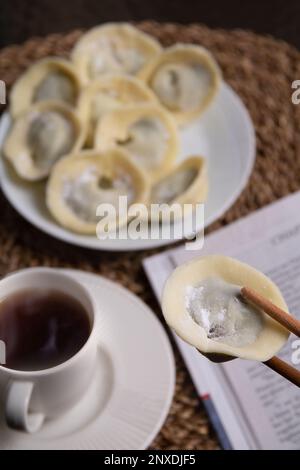 prenez des photos de nombreux bonbons au chocolat sous forme de boulettes sur une assiette à côté d'un livre et d'une tasse de café avec une boisson sur un support en osier Banque D'Images