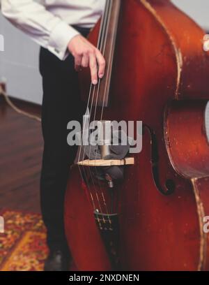 Joueur de violoncelliste contrabass dans les écouteurs pendant la répétition, enregistrement de son pour la nouvelle chanson d'album au studio, violoncelliste musicien avec microphone a Banque D'Images