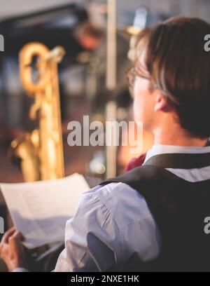 Orchestre musicien de jazz pendant la représentation, répétition de l'enregistrement sonore, saxophoniste jouant des notes musicales sur papier, avant le concert, mu Banque D'Images