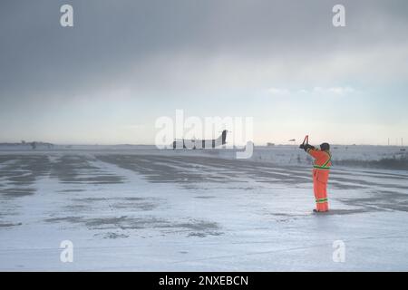 Un travailleur guide un avion turbopropulseur bi-moteur ATR 72 sur la piste de l'aéroport de Churchill (CEYQ, YYQ) à Churchill, au Manitoba, au Canada. Banque D'Images