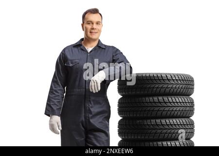 Auto mécanicien sur une position uniforme et appuyé sur une pile de pneus isolés sur fond blanc Banque D'Images