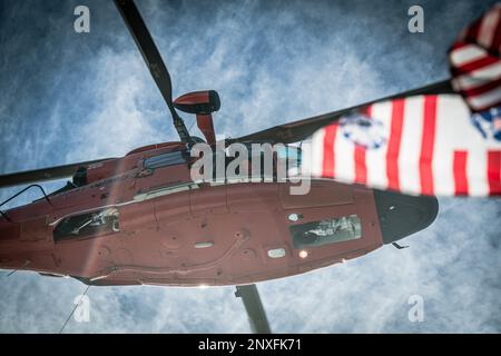 A ÉTATS-UNIS L'hélicoptère Dolphin de la Garde côtière Eurocopter MH-65 de la station aérienne Savannah survole un drapeau de la Garde côtière lors de l'entraînement des opérations d'hélicoptère à Charleston Harbour, Caroline du Sud, le 5 janvier 2023. L'évacuation par hélicoptère est un moyen plus rapide de transporter des personnes à un niveau de soins plus élevé. Banque D'Images