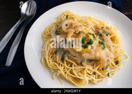 Piccata de poulet servi sur Spaghetti sur une assiette : poulet, oignons et citrons dans une sauce à l'ail et au vin blanc Banque D'Images