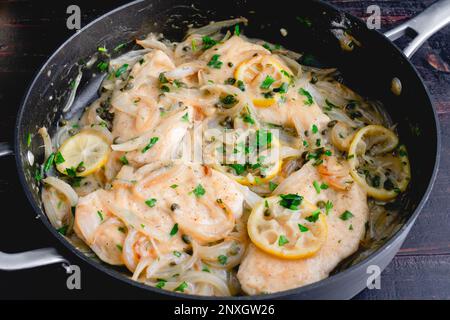 Piccata de poulet cuit dans un grand poêlé de saute : escalets de poulet et tranches de citron cuits dans une sauce au vin blanc avec câpres Banque D'Images