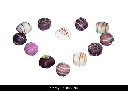 Variété de truffes au chocolat pralines isolées sur fond blanc. Disposés en forme de cœur. Banque D'Images