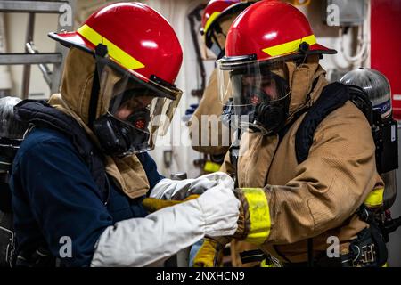 Technicien d'entretien de la coque 3rd classe Naomi Nanez, à gauche, affecté au navire de transport amphibie de classe San Antonio USS Arlington (LPD 24), aide le spécialiste du personnel 2nd classe Juliette Parissi, également affecté à Arlington, don matériel de lutte contre les incendies lors d'un exercice de trimestres généraux effectué dans l'océan Atlantique, 10 février 2023. Les marins d'Arlington maintiennent la maîtrise des dommages en effectuant des exercices de routine à la fois à l'intérieur et en cours. Banque D'Images