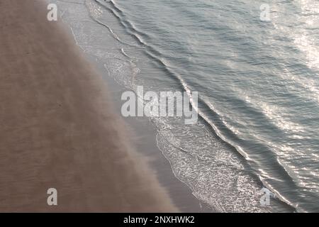 Vagues sur une plage colorée du golfe Persique aux couleurs rouge et bleu Banque D'Images