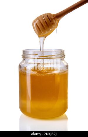 Miel goutte de miel en bois de la louche de miel dans le pot de verre, miel d'acacia isolé sur blanc avec le chemin de coupure Banque D'Images