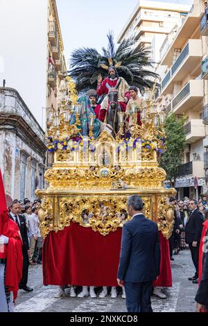 Huelva, Espagne - 10 avril 2022: Trône ou plate-forme de l'odepa de Jésus-Christ, en compagnie d'un âne de la Confrérie de la Borriquita, dans le su des palmiers Banque D'Images