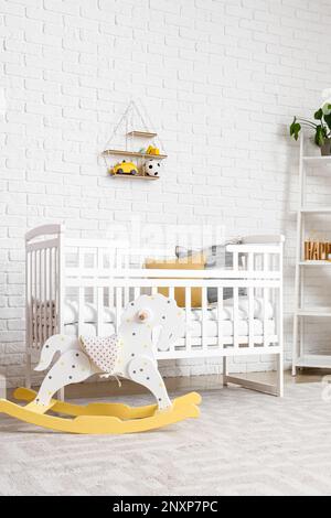 Intérieur de la chambre des enfants avec lit de bébé et cheval à bascule Banque D'Images