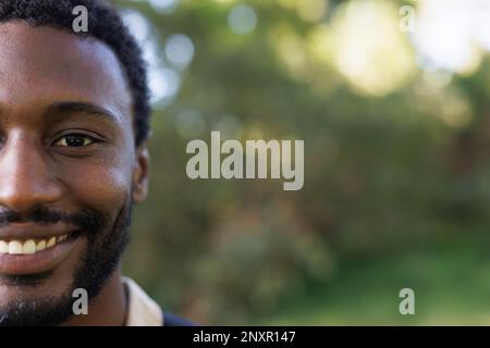 Portrait à moitié face d'un homme afro-américain souriant trekking dans la forêt, espace copie Banque D'Images