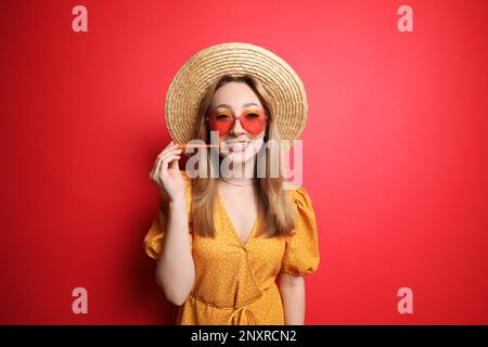 Jeune femme à la mode mâchant du bubblegum sur fond rouge Banque D'Images