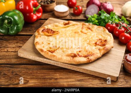 Délicieux khachapuri avec fromage et légumes sur une table en bois Banque D'Images