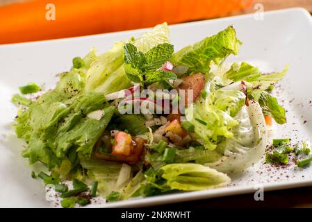 salade arabe avec tissu orange et assiette blanche, tomate, oignon, ciboulette, persil, radis, menthe, olive, poulet. Banque D'Images