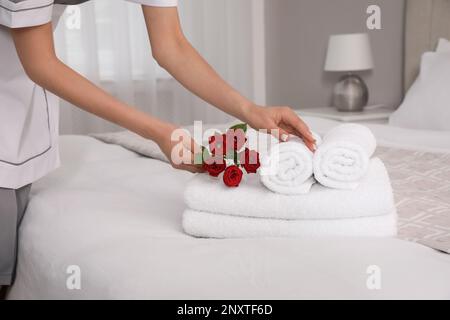 Femme de chambre en train de mettre des fleurs avec des serviettes fraîches dans la chambre d'hôtel, en gros plan Banque D'Images