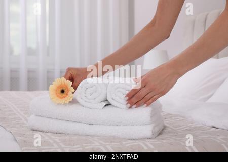 Femme de chambre en train de mettre des fleurs avec des serviettes fraîches dans la chambre d'hôtel, en gros plan Banque D'Images