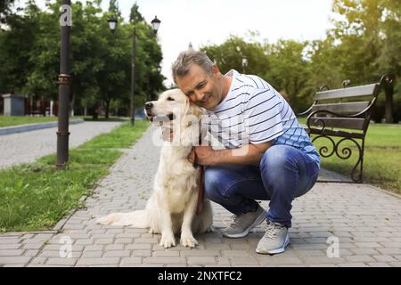 Un homme âgé heureux avec son chien Golden Retriever dans le parc Banque D'Images