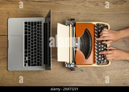 Femme utilisant une vieille machine à écrire près d'un ordinateur portable à une table en bois, vue de dessus. Concept de progrès technologique Banque D'Images