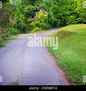 Un bâtiment rustique de deux étages se trouve dans la courbe d'une route dans le Tennessee rural. Le bâtiment est abandonné et surcultivé. Banque D'Images