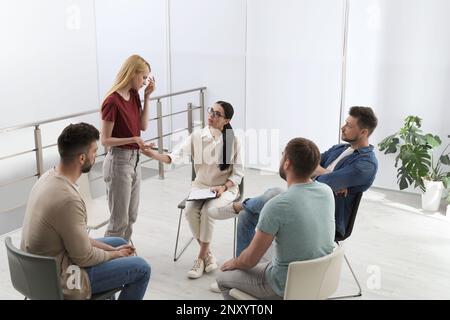 Psychothérapeute travaillant avec un groupe de personnes toxicomanes à la séance de thérapie à l'intérieur Banque D'Images