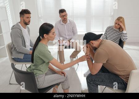 Psychothérapeute travaillant avec un groupe de personnes toxicomanes à la séance de thérapie à l'intérieur Banque D'Images