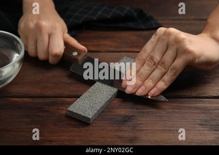 Femme aiguisant couteau à table en bois, gros plan Banque D'Images
