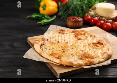 Délicieux khachapuri au fromage et aux légumes sur une table en bois sombre Banque D'Images