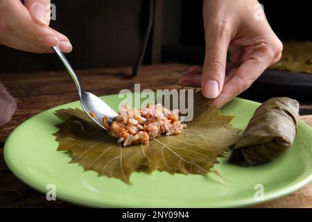 Femme préparant des feuilles de raisin farcies sur l'assiette, gros plan Banque D'Images