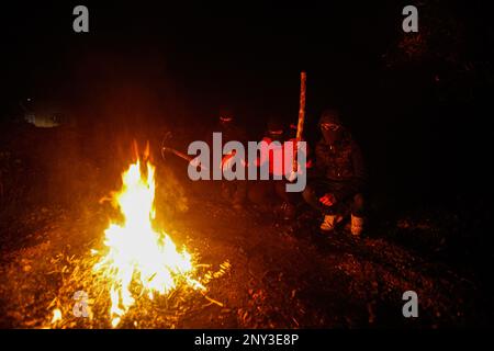 Naplouse, Palestine. 01st mars 2023. Des Palestiniens masqués portant des bâtons de bois autour du feu se tiennent sur garde pendant la nuit pour repousser les attaques des colons juifs, au sud de Naplouse, en Cisjordanie. Les attaques de colons se sont intensifiés contre les Palestiniens, en particulier les villages au sud de Naplouse, comme Hawara Burin, le dernier d'entre eux a été sur la ville de Hawara, dont les dommages ont été causés par l'incendie de dizaines de maisons et de boutiques et plus d'une centaine de voitures. Le Premier ministre palestinien Muhammad Shtayyeh a déclaré que les pertes totales étaient estimées à près de $5 millions. Crédit : SOPA Images Limited/Alamy Live News Banque D'Images