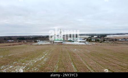Hiver initial. Clip.View d'un drone sur un paysage avec de l'herbe neigeuse dans un champ où il y a un temple avec une croix dorée sur un dôme doré contre Banque D'Images