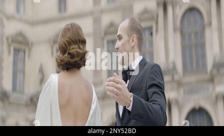 Danse couple joyeux. Action. Une belle brune dans une robe blanche et sa fiancée rient et s'amusent sur la place d'une ville bâtie. Élevée Banque D'Images