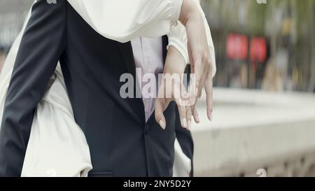 Danse couple joyeux. Action. Une belle brune dans une robe blanche et sa fiancée rient et s'amusent sur la place d'une ville bâtie. Élevée Banque D'Images