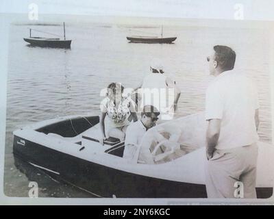 FILE- In this undated file photo provided by Guernsey's, John F. Kennedy is at the wheel of his speedboat, Restofus. Hot memorabilia with a Cold War theme, including property of the late President John F. Kennedy and CIA pilot Francis Gary Powers, is being featured at an auction in New York City on Saturday, Oct. 7, 2017. (Guernsey's via AP)
