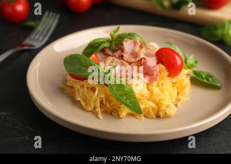 Courge spaghetti savoureuse au bacon et au basilic servi sur une table noire, en gros plan Banque D'Images