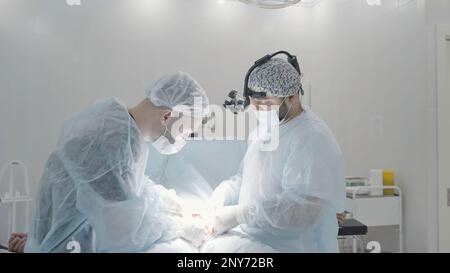 Vue latérale des chirurgiens masculins dans la salle d'opération d'un hôpital. Action. Concept de médecine chirurgie et santé Banque D'Images