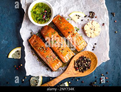 Délicieux filet de saumon frit, assaisonnements sur fond de béton rustique bleu. Steak de saumon cuit au poivre, aux herbes, au citron, à l'ail et à l'huile d'olive Banque D'Images