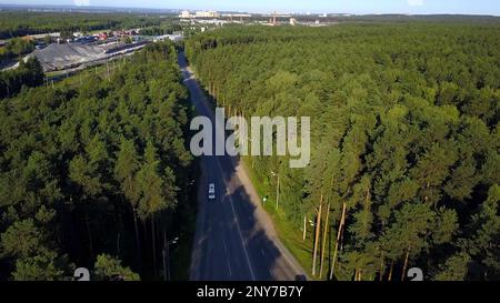 Vue aérienne des voitures voyageant sur un magnifique terrain boisé. Attache. Véhicules roulant sur une route asphaltée avec un beau paysage Banque D'Images