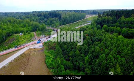 Vue aérienne des voitures voyageant sur un magnifique terrain boisé. Attache. Véhicules roulant sur une route asphaltée avec un beau paysage Banque D'Images