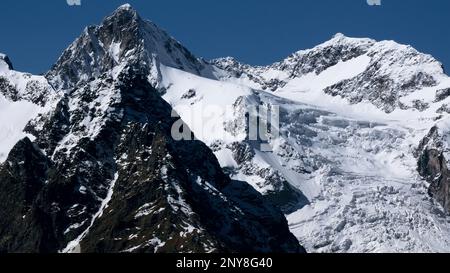 Vue aérienne des montagnes couvertes de neige d'hiver sur fond bleu. Créatif. Pentes et falaises abruptes Banque D'Images