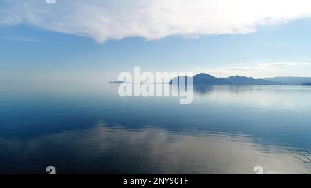 Vue imprenable depuis la prairie sur une surface d'eau calme et bleu foncé. Prise de vue. Le ciel bleu se reflète dans l'eau calme du lac Banque D'Images