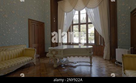 Intérieur rétro d'une chambre à l'ancienne. Action. Canapé et piano à queue contre de grandes fenêtres Banque D'Images