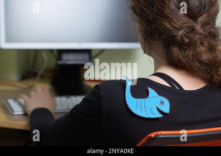 Journée internationale de la Fool. Femme sur le lieu de travail dans le bureau avec un poisson collé sur son dos Banque D'Images