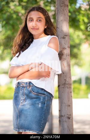 Belle adolescente penchée sur un arbre qui regarde loin Banque D'Images