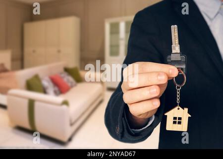 agent immobilier donne les clés sur le fond de la salle de séjour avec un intérieur à la mode. Le realteur tient dans sa main une clé avec une clé Banque D'Images