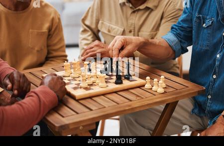 Mains, échecs et amis dans les jeux de société sur table en bois pour la compétition stratégique, le mouvement tactique ou la décision. Main d'un joueur de stratégie qualifié tenant Banque D'Images